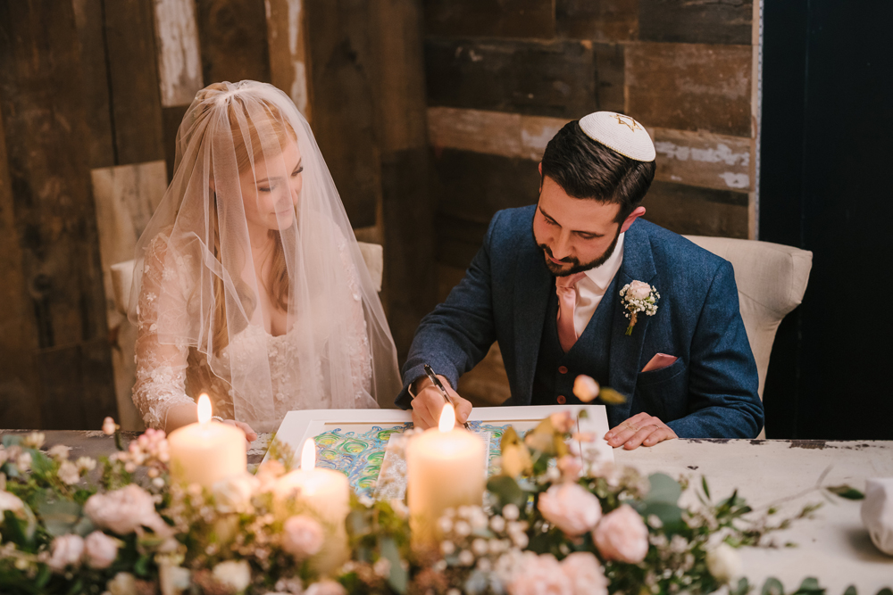 7. A photo capturing the moment of the Ketubah signing, with the bride, groom, and witnesses visible.